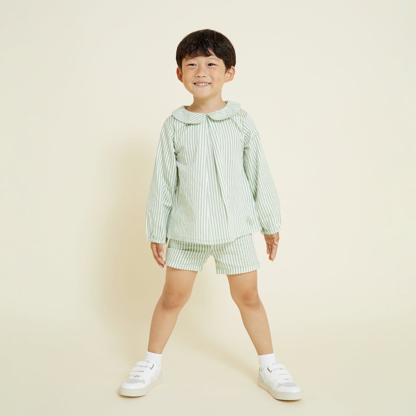 5 year old boy wearing casual pull on short in sage and milk white stripe, paired with collared shirt in a matching set