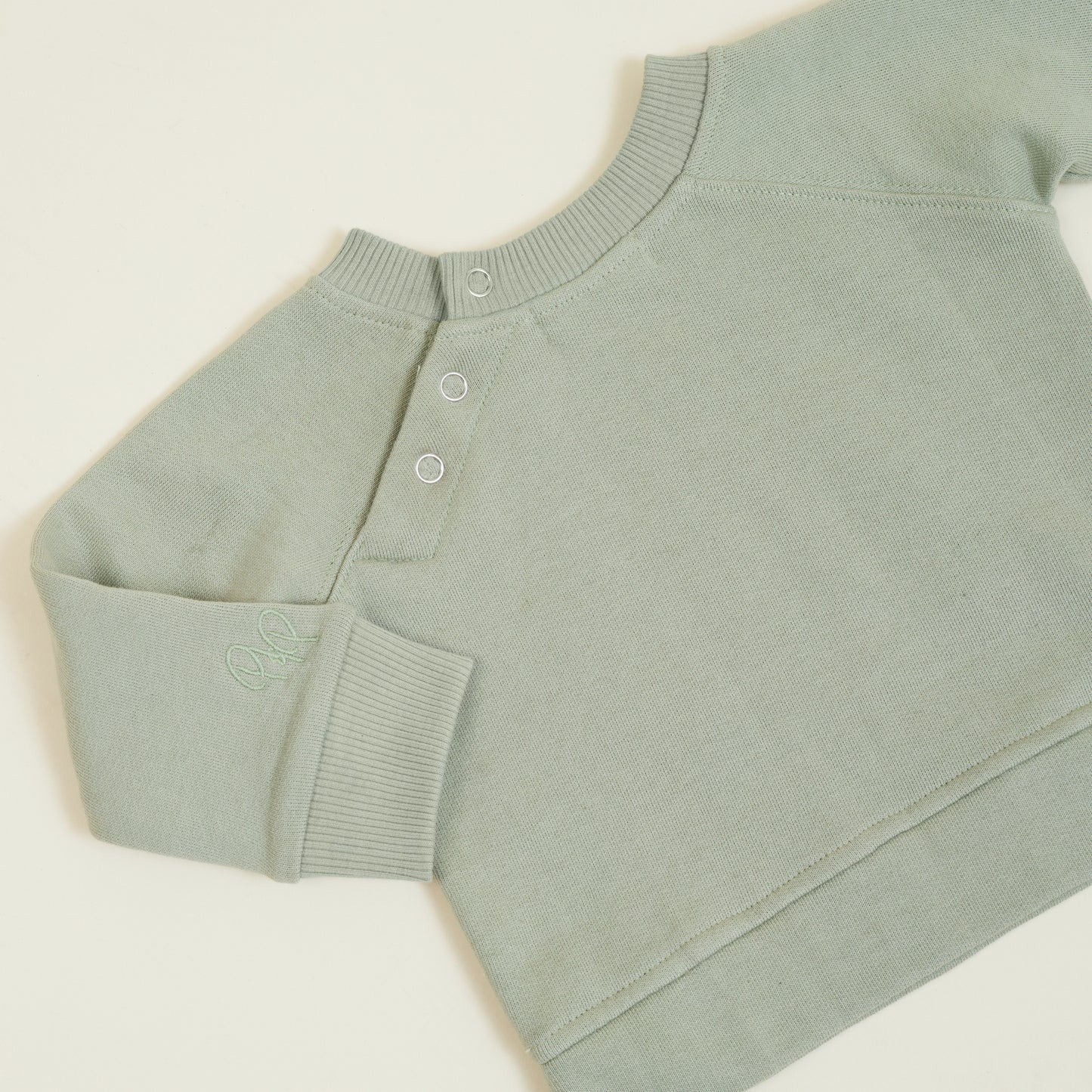 Button detail of sage green sweatshirt