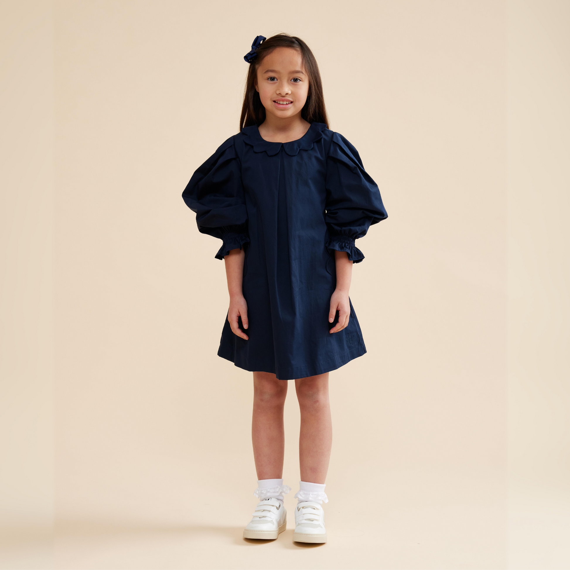 Young girl wearing navy scallop detail smock dress