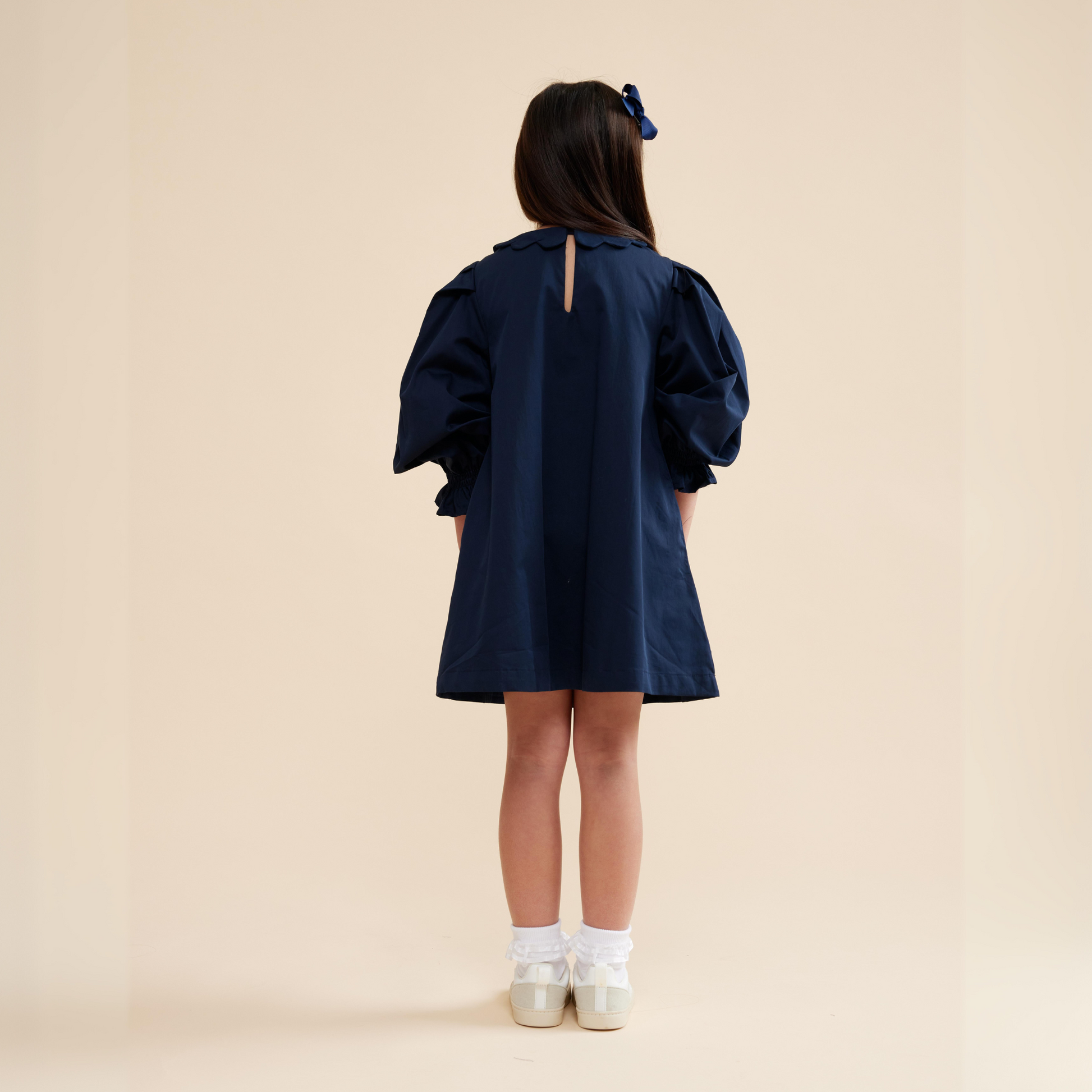 Back view of navy scallop detail smock dress with scallop collar and pocket details, long sleeves and knee length dress