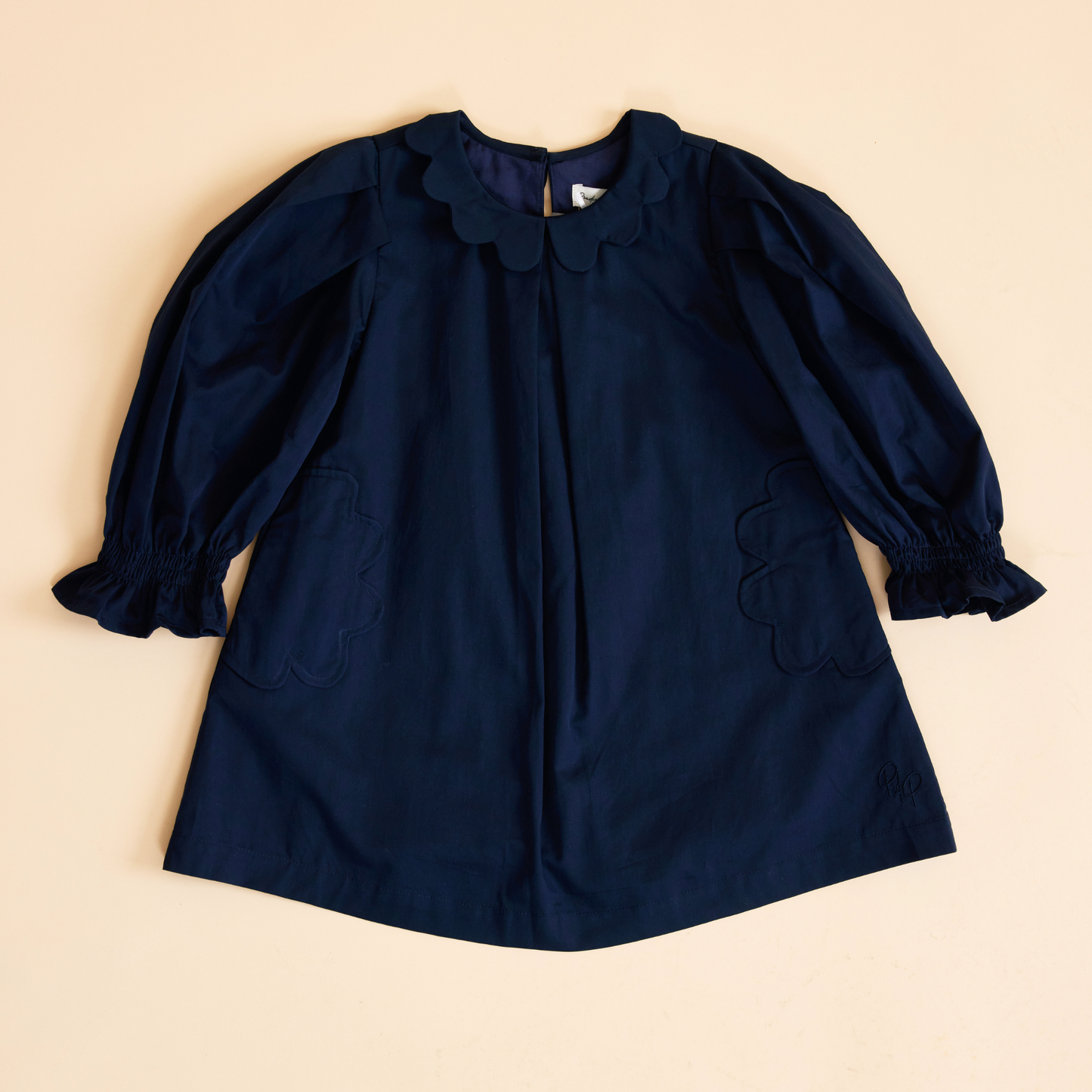 Flat lay of navy scallop detail smock dress, front view showing scalloped neckline, scallop detailing on the pockets and a relaxed fit