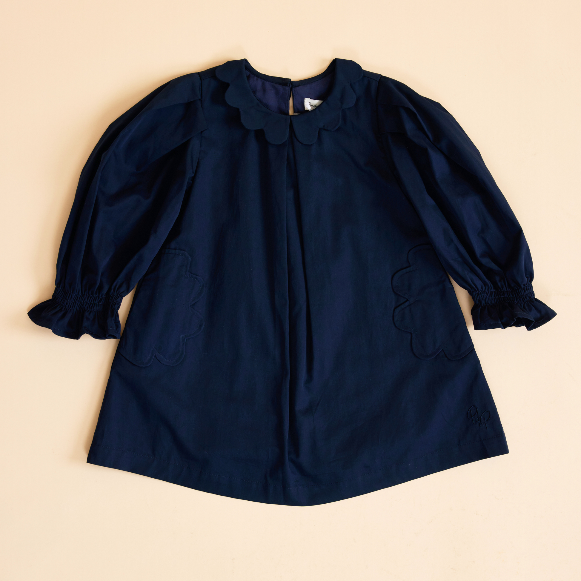 Flat lay of navy scallop detail smock dress, front view showing scalloped neckline, scallop detailing on the pockets and a relaxed fit