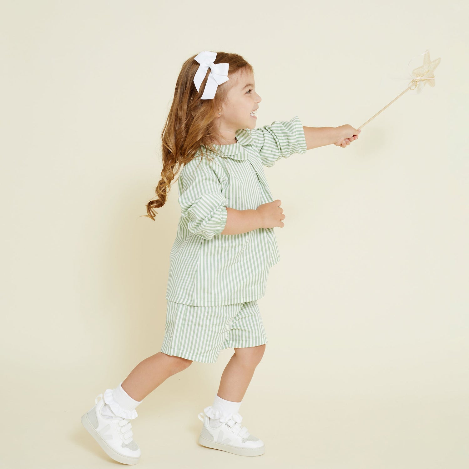 Little girl wearing white hair bow in her hair, playing with a fairy wand
