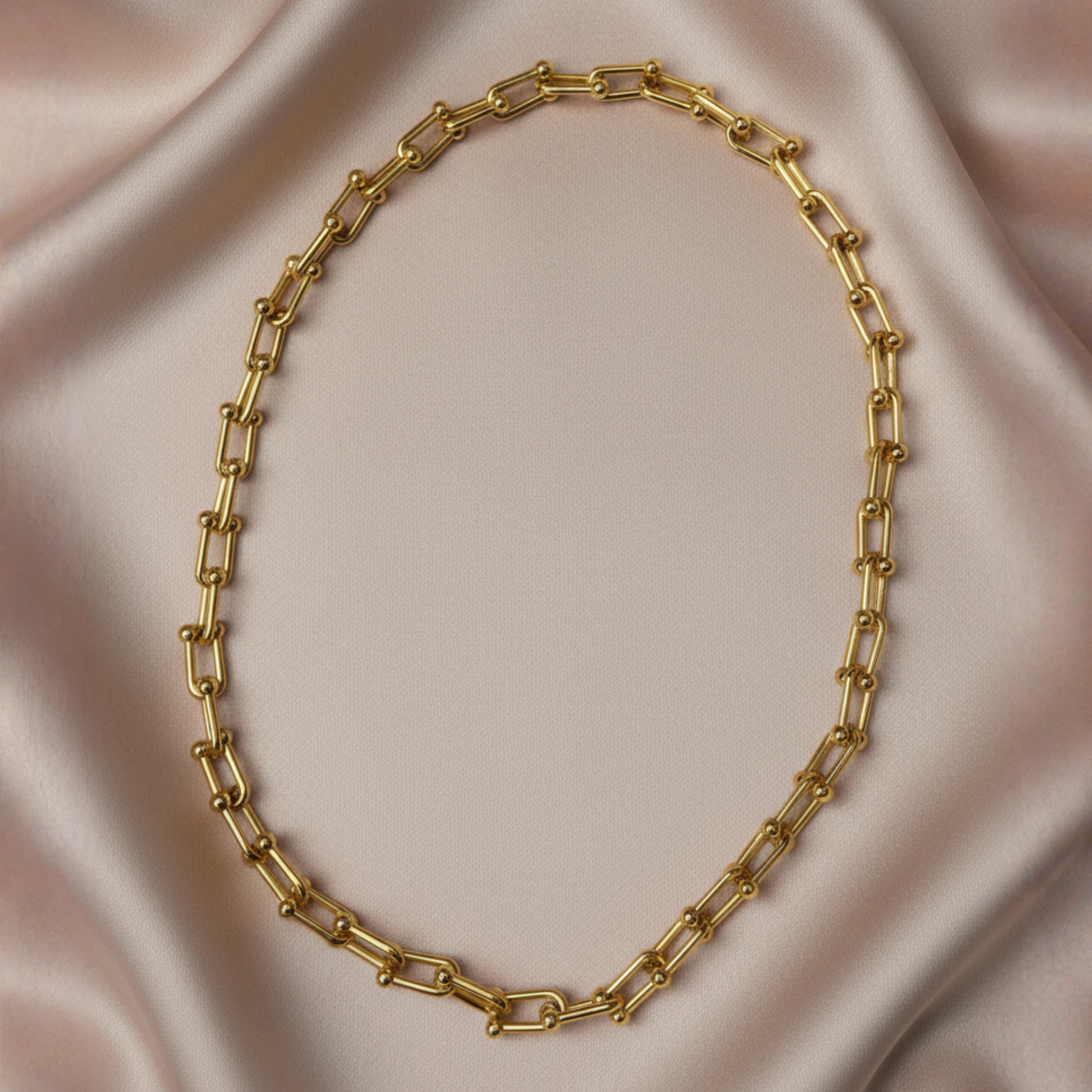 18K gold plated chunky modern chain necklace resting on luxurious silk background