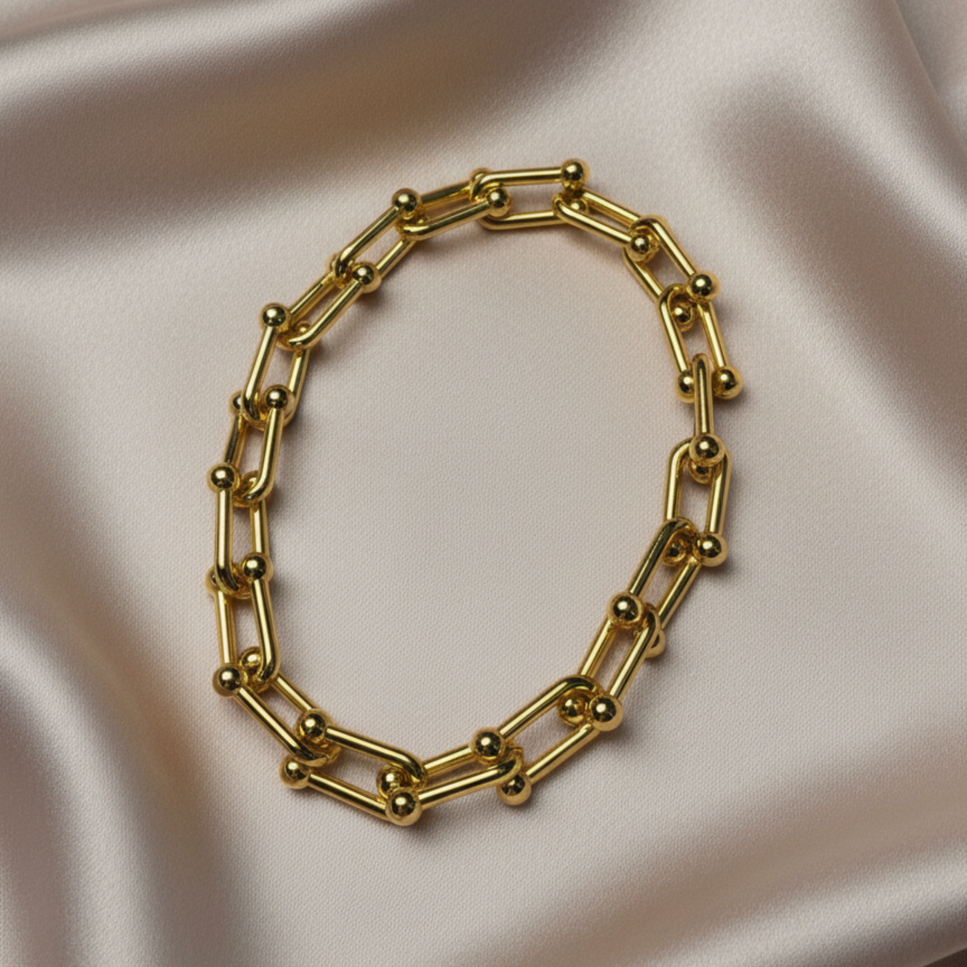 An 18k gold plated modern geometric chunky bracelet sits atop a luxurious silk backround