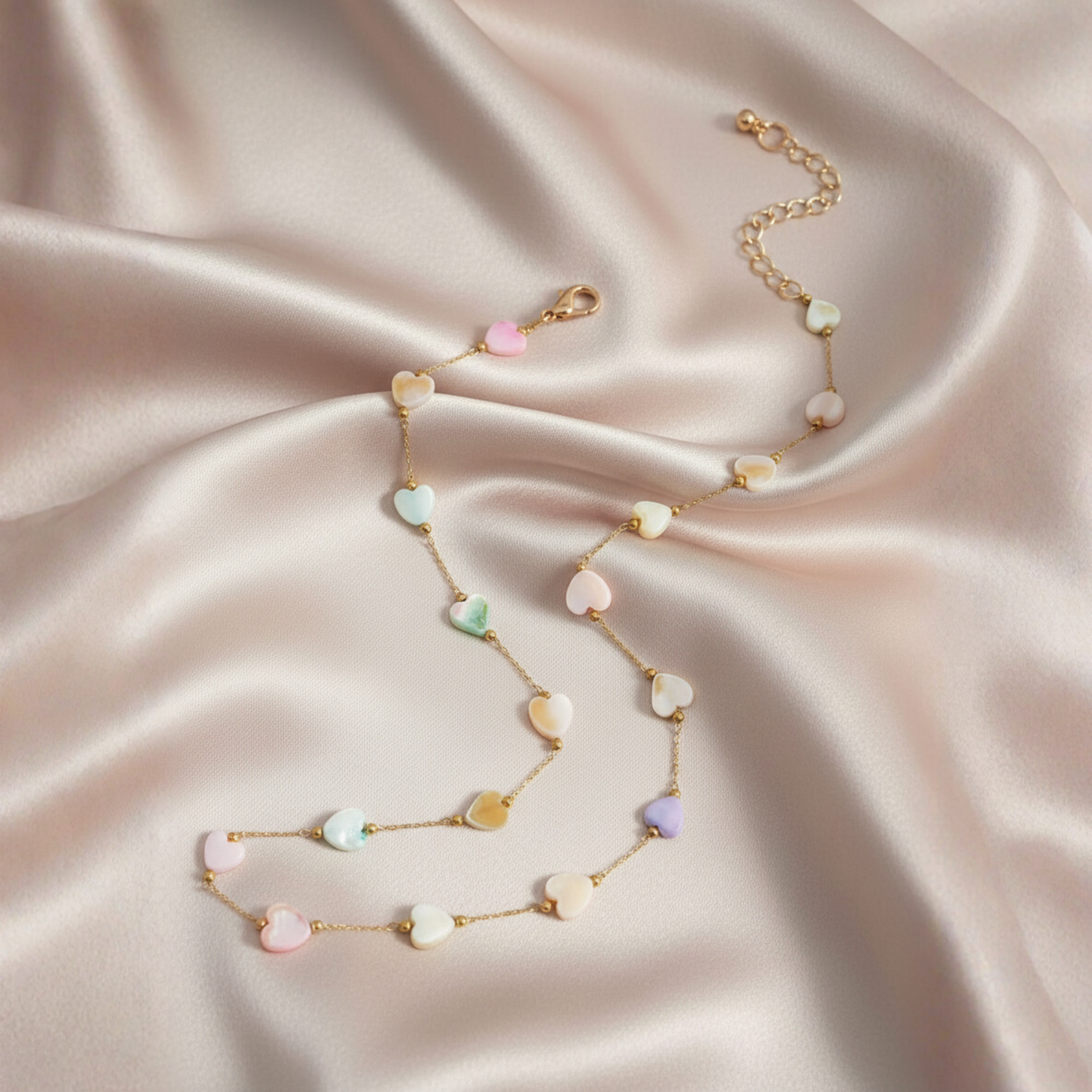 Necklace with pastel-colored beads on a soft pink fabric background