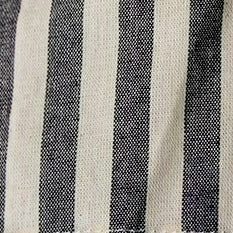 A pair of striped shorts hanging from gold hangers on a clothing rack, featuring vertical stripes in dark gray and cream with a cream tie waist. A navy blue garment is partially visible on the left.