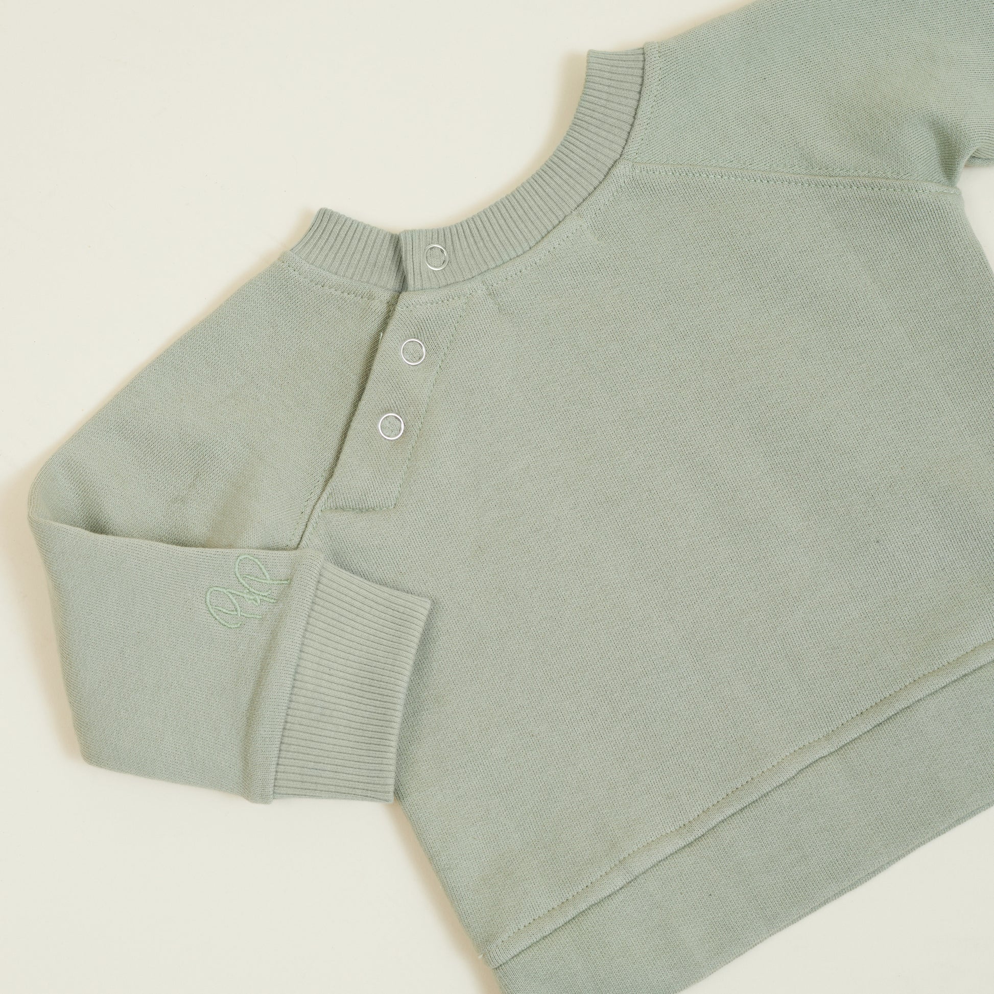 Button detail of sage green sweatshirt