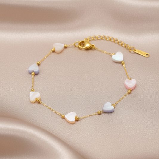 Gold bracelet with heart-shaped beads on a beige fabric background