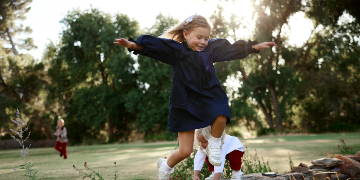 Child in a blue dress running outdoors with trees in the background